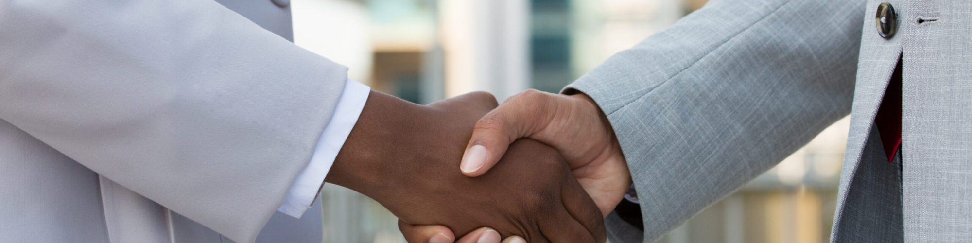Multiethnic leaders greeting each other in city. Closeup of business man and woman shaking hands outside. Cooperation concept